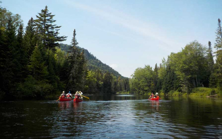 a group of three canoes manned by veterans navigates water on an outward bound trip